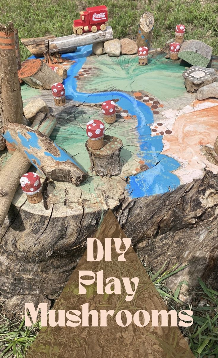 an outdoor play area made out of logs and rocks with red mushrooms on them, in the grass