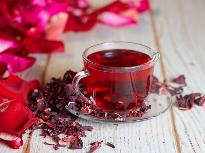 a glass cup filled with red tea sitting on top of a wooden table