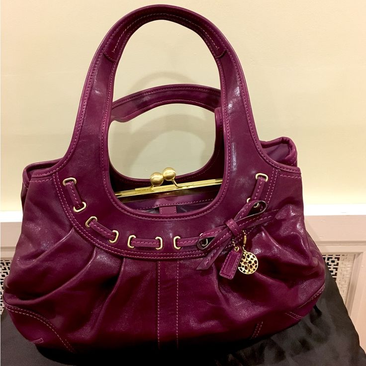 Beautiful Spacious Coach Genuine Leather Handbag With 3 Roomy Compartments. Bag Designed With A Unique Kiss Lock Completing The Middle Compartment In Color Plum. Bag In Excellent Condition And Used Only Once To A Dinner Event Then Kept Protected In Its Dust Bag (Included) And Stored In Container, In A Smoke-Free Home. Designer Purple Bag With Gold-tone Hardware, Designer Purple Bags With Gold-tone Hardware, Purple Leather Shoulder Bag With Detachable Handle, Elegant Purple Bags With Gold-tone Hardware, Purple Satchel With Gold-tone Hardware For Daily Use, Purple Leather Handheld Shoulder Bag, Handheld Purple Leather Satchel, Handheld Purple Leather Shoulder Bag, Chic Purple Leather Shoulder Bag