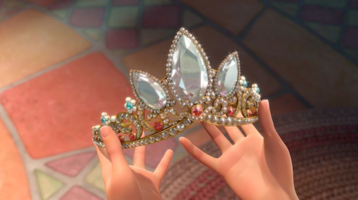 a close up of a person's hand holding a tiara