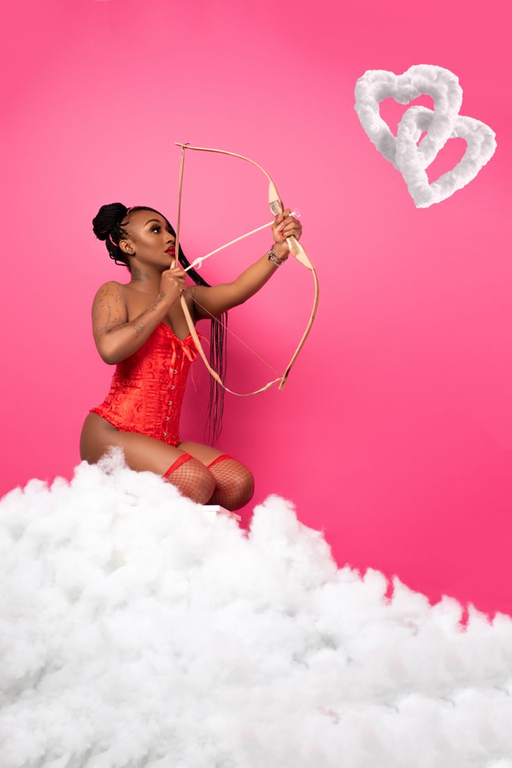 a woman sitting on clouds holding a bow and arrow