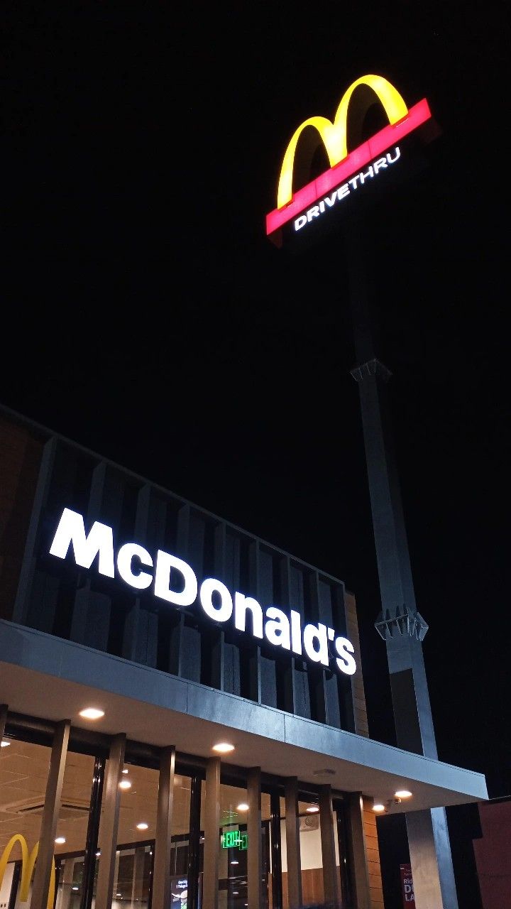 the mcdonald's sign is lit up at night