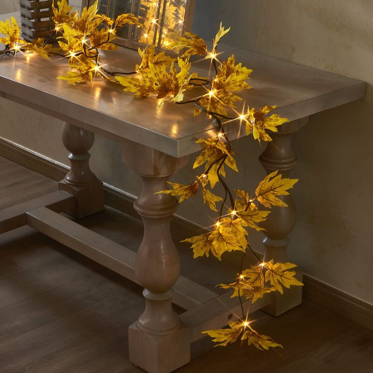 a table with some lights on it and leaves hanging from the top, along with other decorations