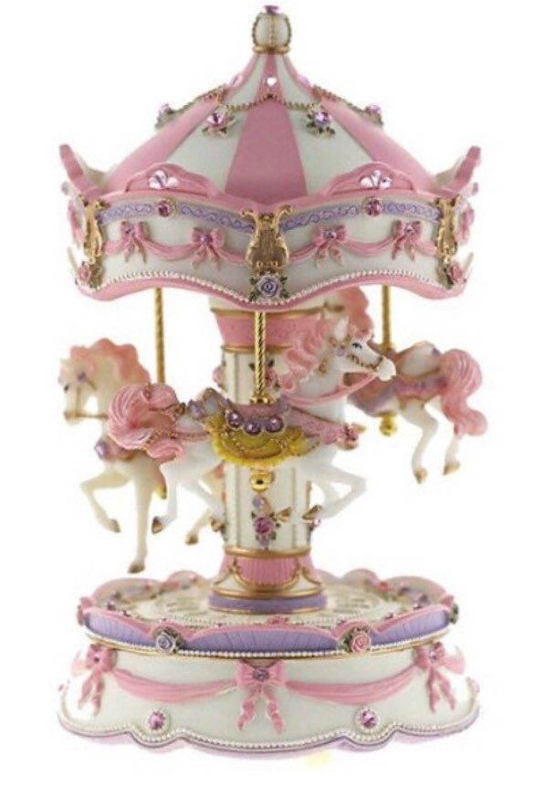 a pink and white carousel with horses on it's sides, in front of a white background