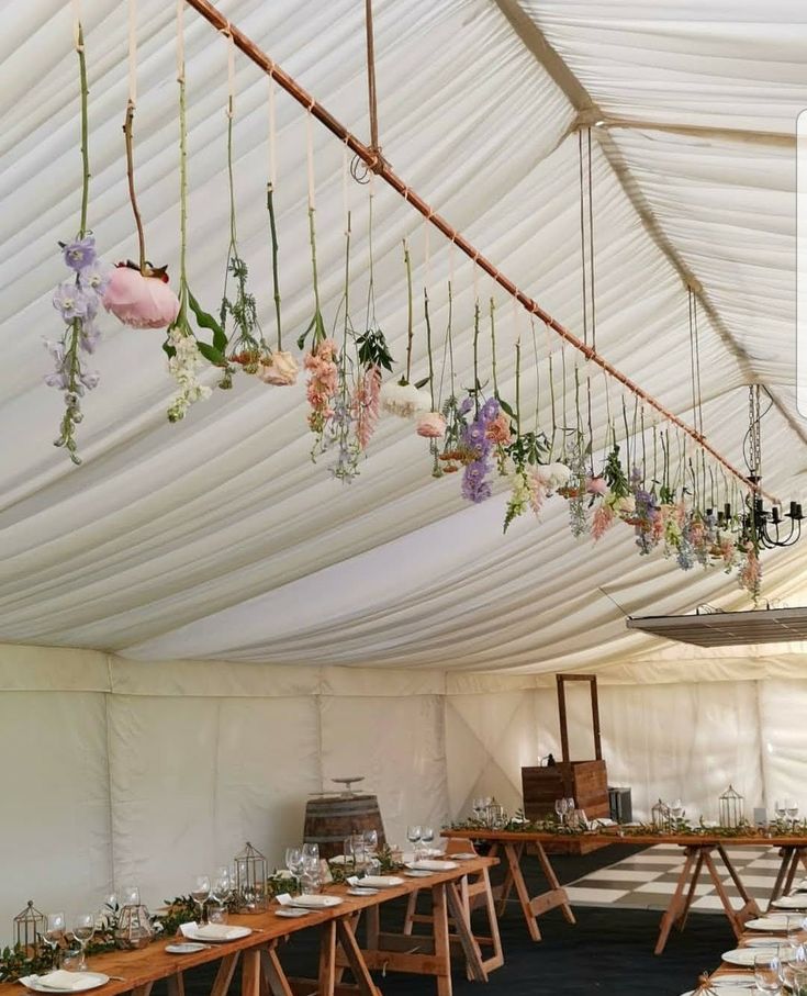 a large tent with tables and flowers hanging from the ceiling