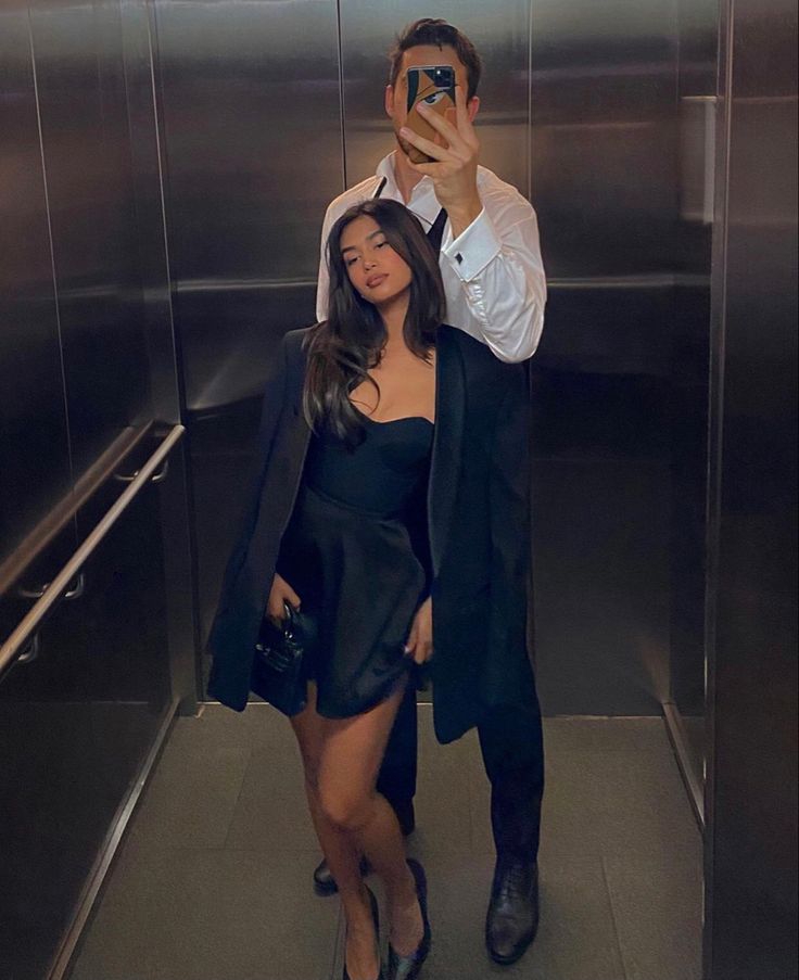 a man taking a selfie with a woman in front of him on the elevator