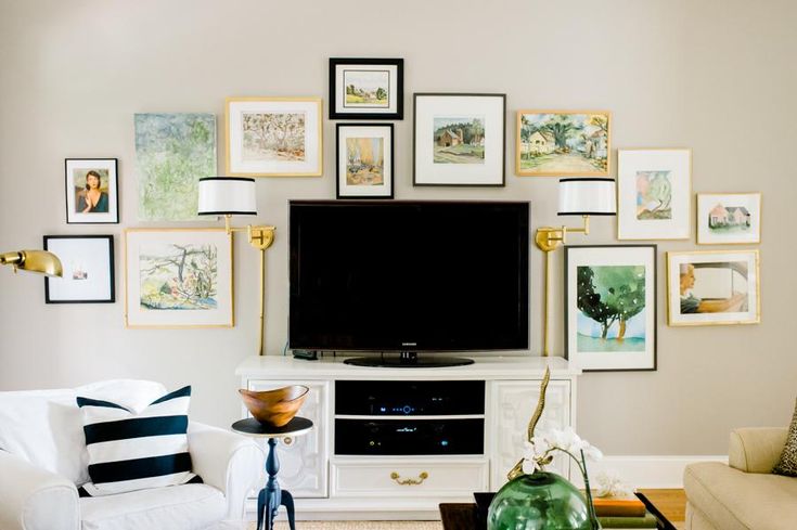 a living room with white furniture and pictures on the wall above it's entertainment center