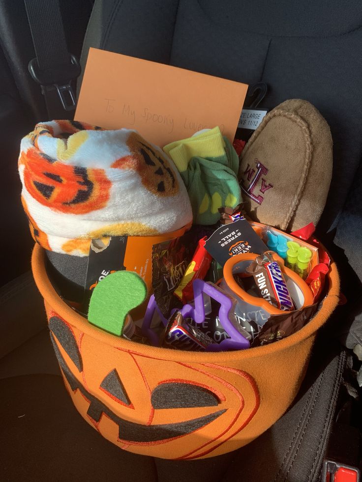 an orange bucket filled with halloween items in the back seat of a car