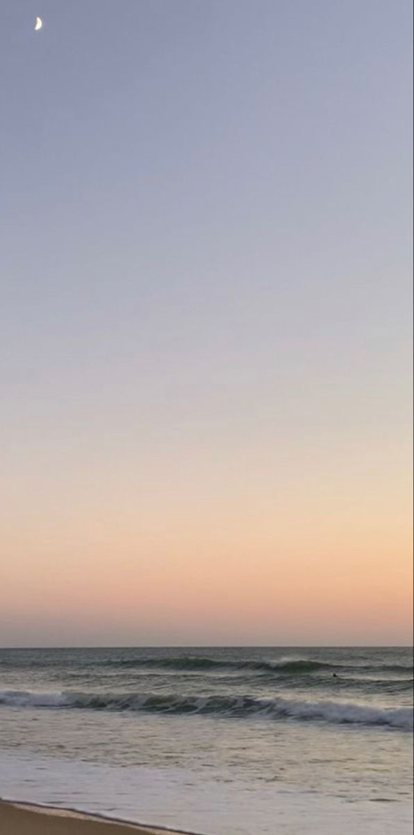 a person standing on the beach with a surfboard under their arm, watching the sun set