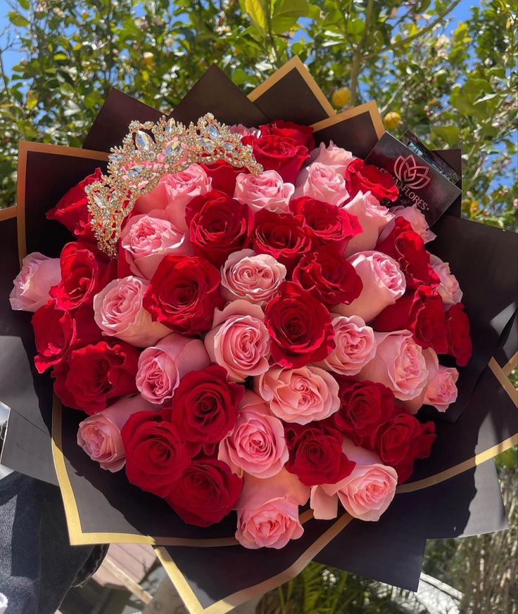 a bouquet of red and pink roses with a tiara