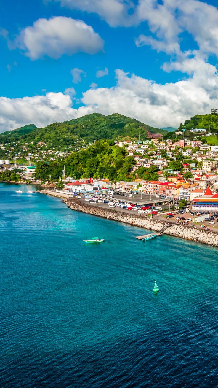 an aerial view of a town on the shore with boats in the water and mountains in the background