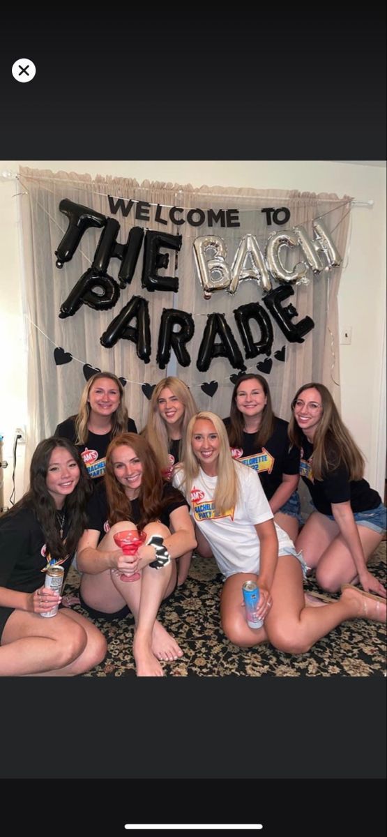 a group of women sitting on top of a bed next to each other in front of a welcome sign