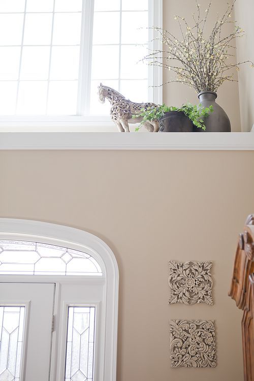 a giraffe standing on top of a window sill next to a vase