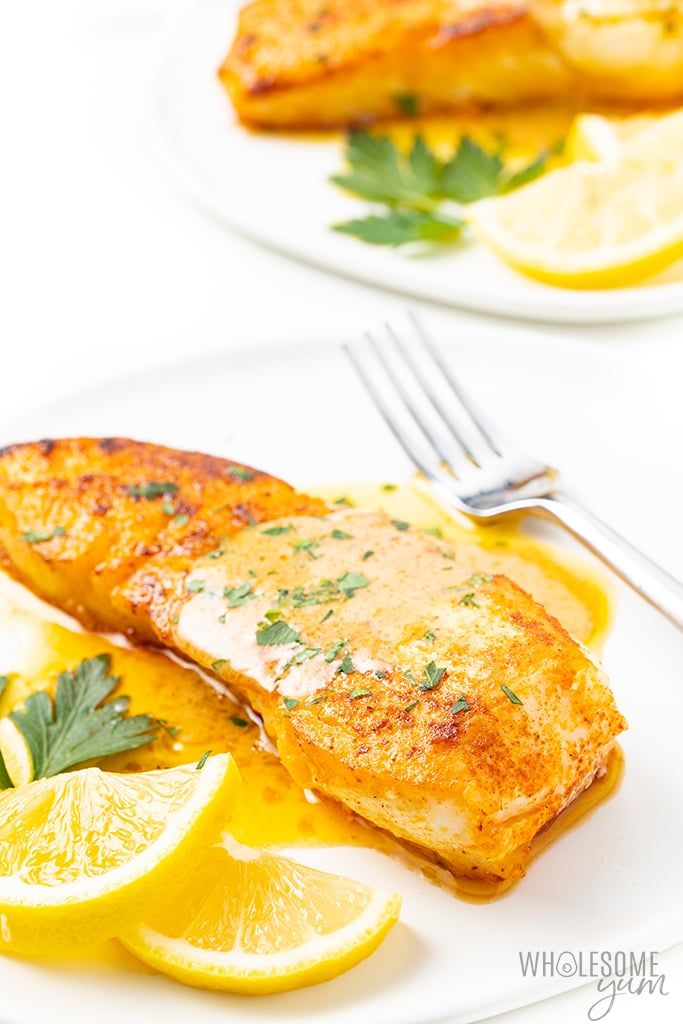 two white plates topped with fish and lemon slices