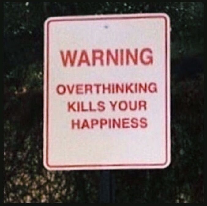 a warning sign posted in front of a bush with trees and bushes behind it that reads, warning overthiking kills your happiness