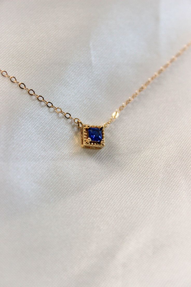 PRODUCT DESCRIPTION Chic and sophisticated, this Diane Necklace is inspired by the glamour of bygone eras. This opulent piece is crafted in 18k Gold-plated or 14k Gold-filled with metal and features a blue square-cut cubic zirconia pendant. Effortlessly elegant and pairs beautifully with day and evening ensembles. You are fine to shower in our gold-filled jewelry. Get it wet, wear it for life! A Dainty yet Elegant Necklace Water and Tarnish Resistant 14k Gold-filled with jeweler's brass (at leas Blue Rectangular Pendant Jewelry For Anniversary, Formal Sapphire Necklace With Rectangular Shape, Blue Rectangular Pendant Fine Jewelry, Elegant Rectangular Gemstone Pendant Jewelry, Elegant Rectangular Pendant Gemstone Jewelry, Blue Rectangular Pendant Jewelry For Formal Occasions, Gold Square Pendant Jewelry For Formal Occasions, Elegant Gold Square Pendant Jewelry, Luxury Blue Square Pendant Necklace