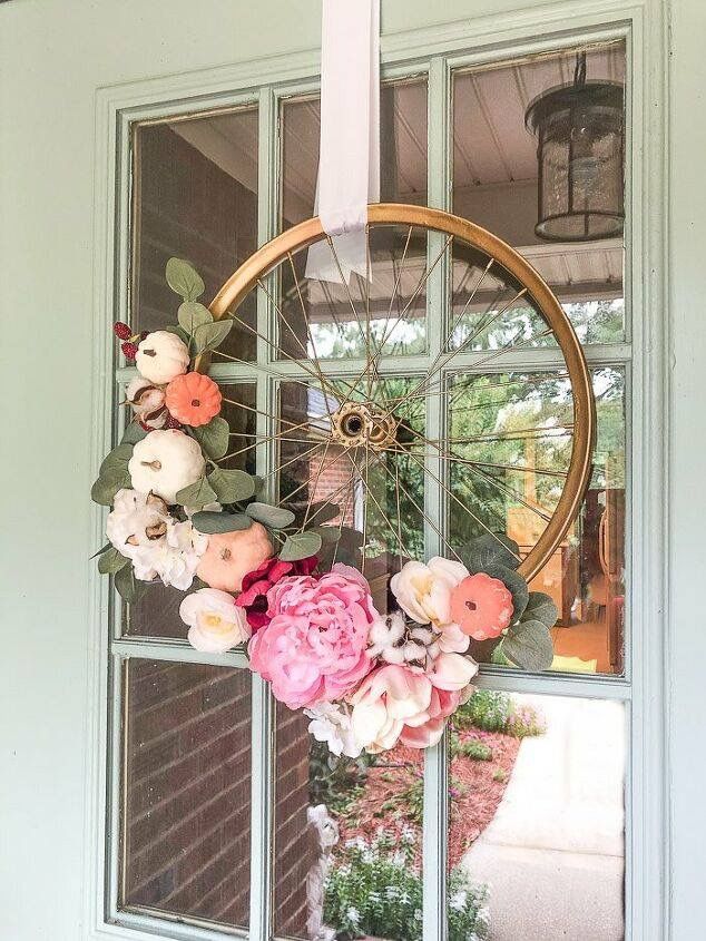 a wreath with flowers hanging from the side of a door next to an open window