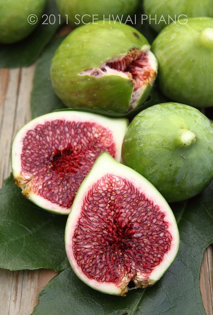 green and red fruit sitting on top of leaves