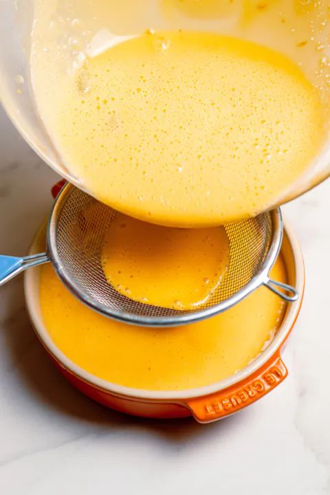 an orange juice is being poured into a strainer