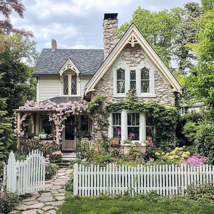 a white picket fence in front of a house with flowers growing on the windows and doors