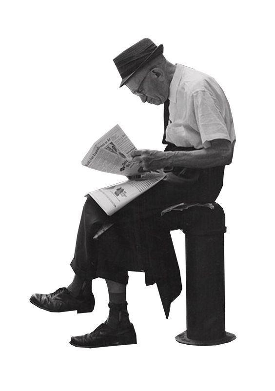 a man sitting on a bench reading a newspaper