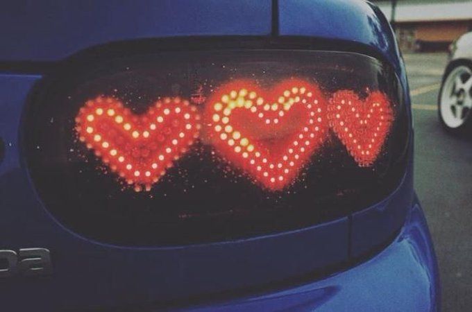 the rear view mirror of a blue car with red lights in the shape of hearts