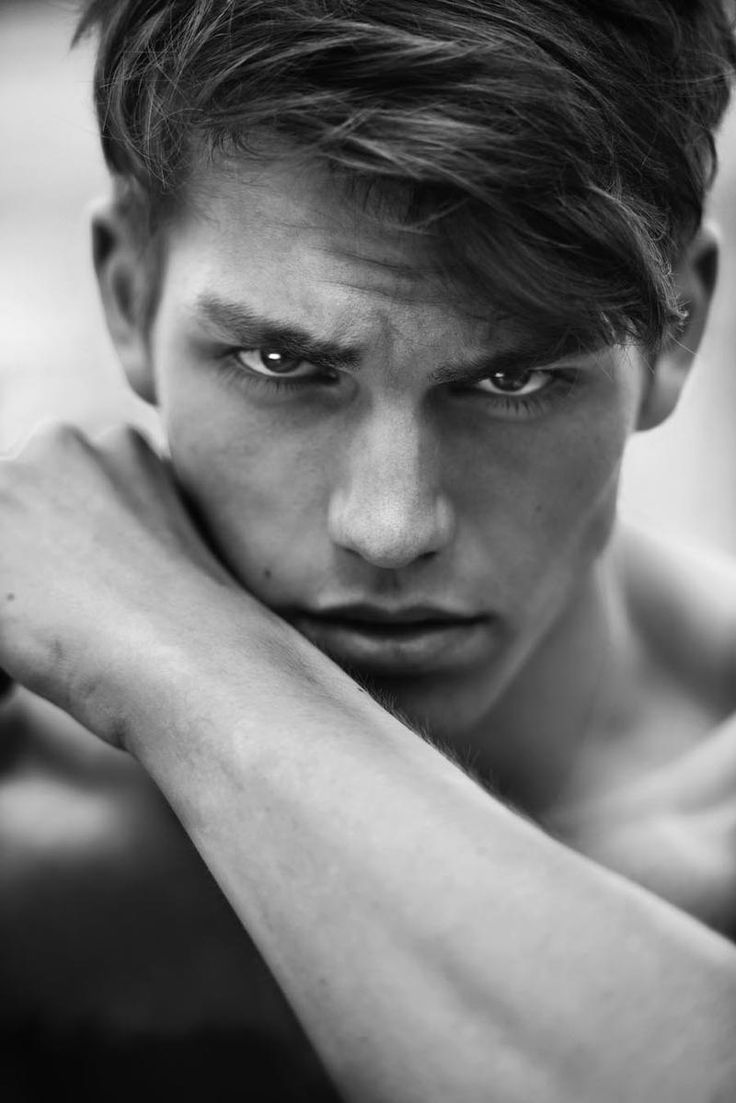 black and white photo of a young man with his arms crossed looking at the camera