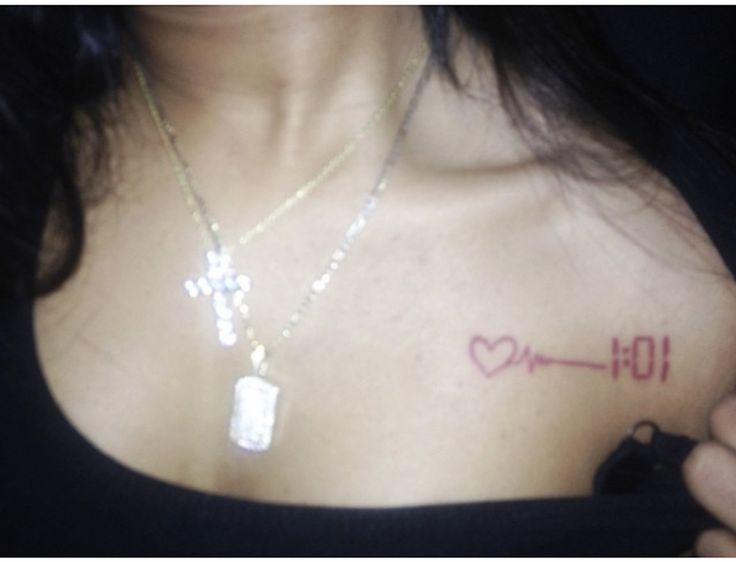 a woman with a heart and arrow tattoo on her chest is holding a cell phone