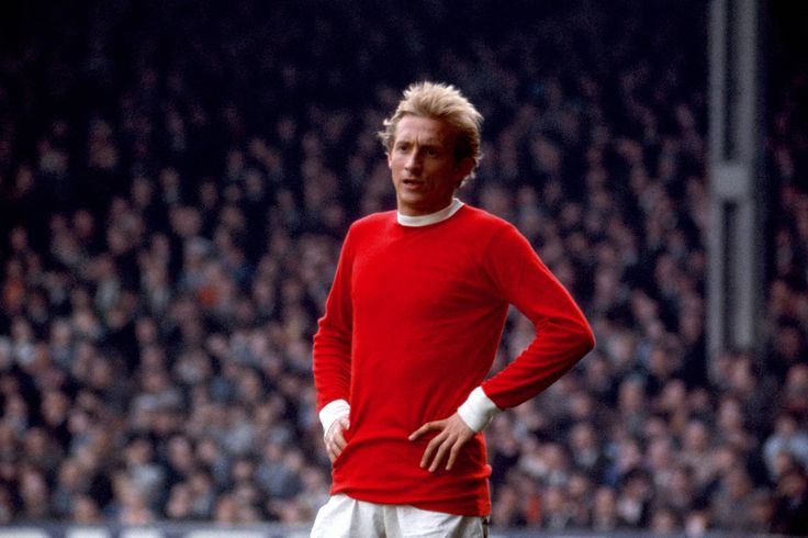 a man standing on top of a soccer field wearing a red shirt and white shorts