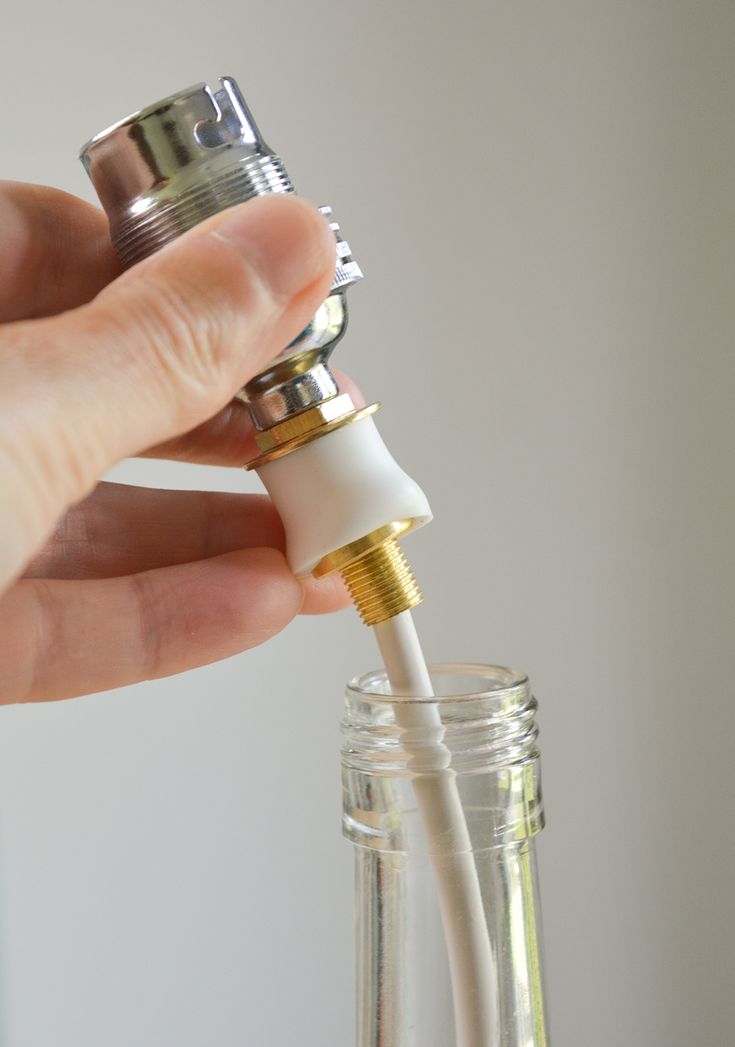 a person is holding an electric toothbrush in a glass jar with water and gold trim