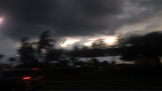 the sun is shining brightly in the dark sky over some trees and cars on the road