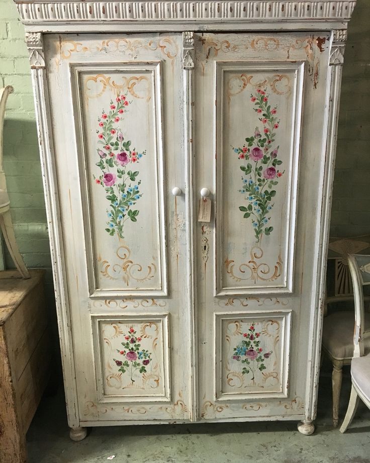 an old white armoire with flowers painted on it