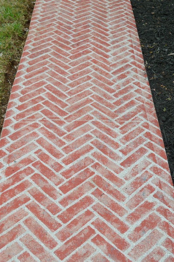 a brick walkway with grass in the background