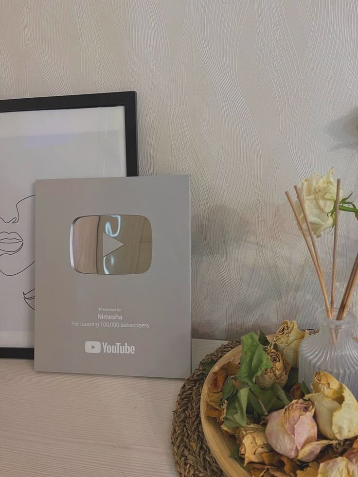 a table topped with a vase filled with flowers next to a box of unidentifiable items