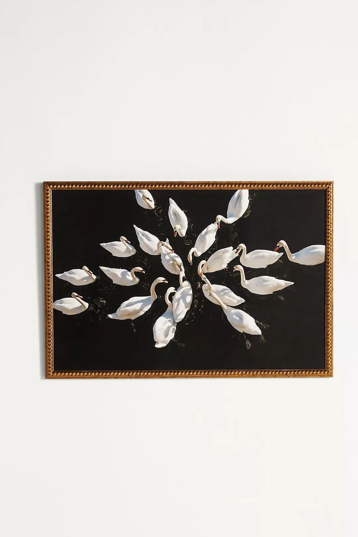 a painting hanging on the wall with white flowers and birds in it's center