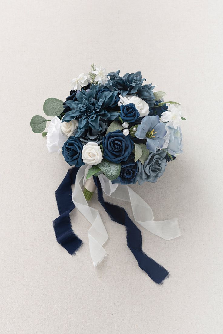 a bridal bouquet with blue and white flowers on the side, tied in ribbon