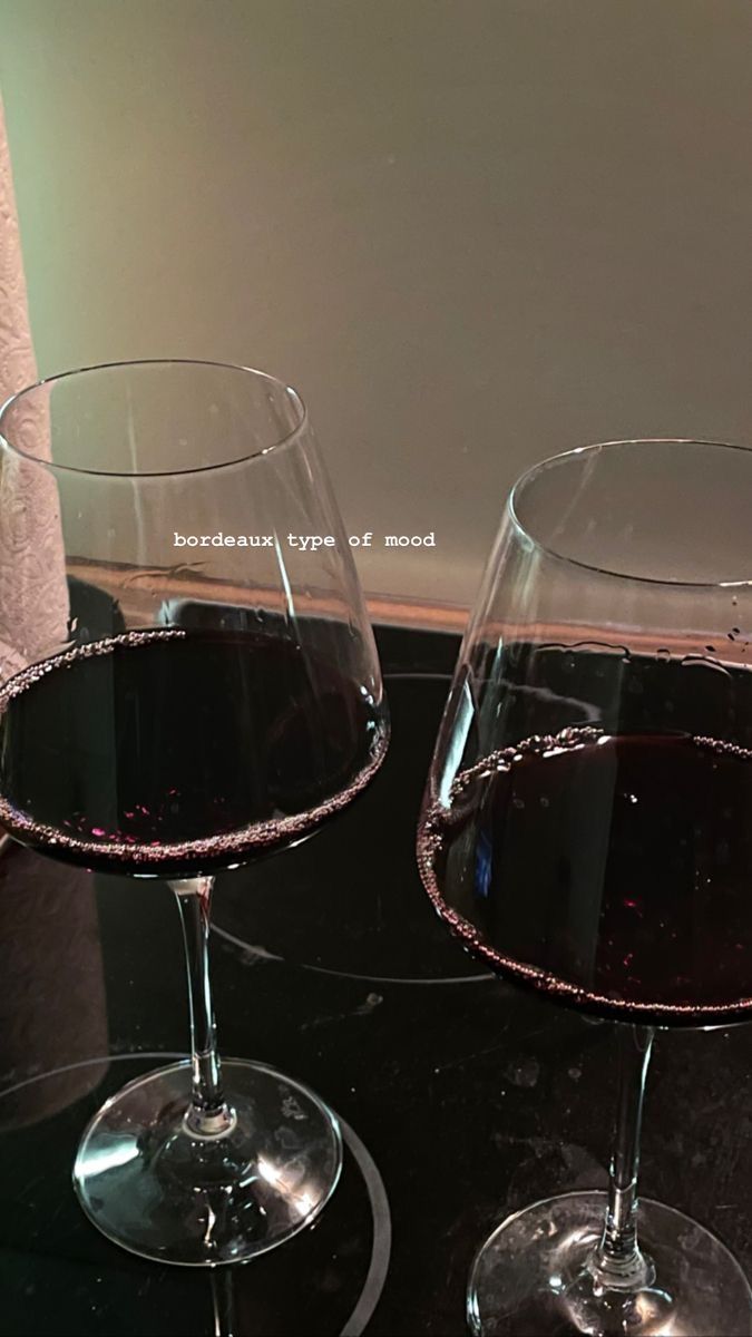 two glasses of wine sitting on top of a table next to each other, one filled with liquid and the other empty