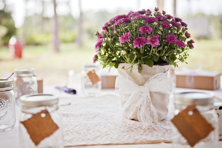 the table is set with mason jars and purple flowers in vases on top of it