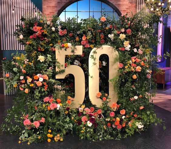 the 50 sign is surrounded by flowers and greenery