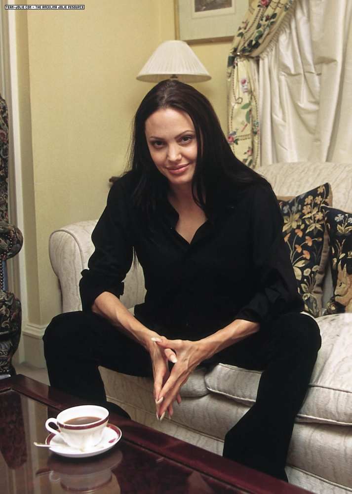 a woman sitting on top of a couch next to a coffee cup and saucer