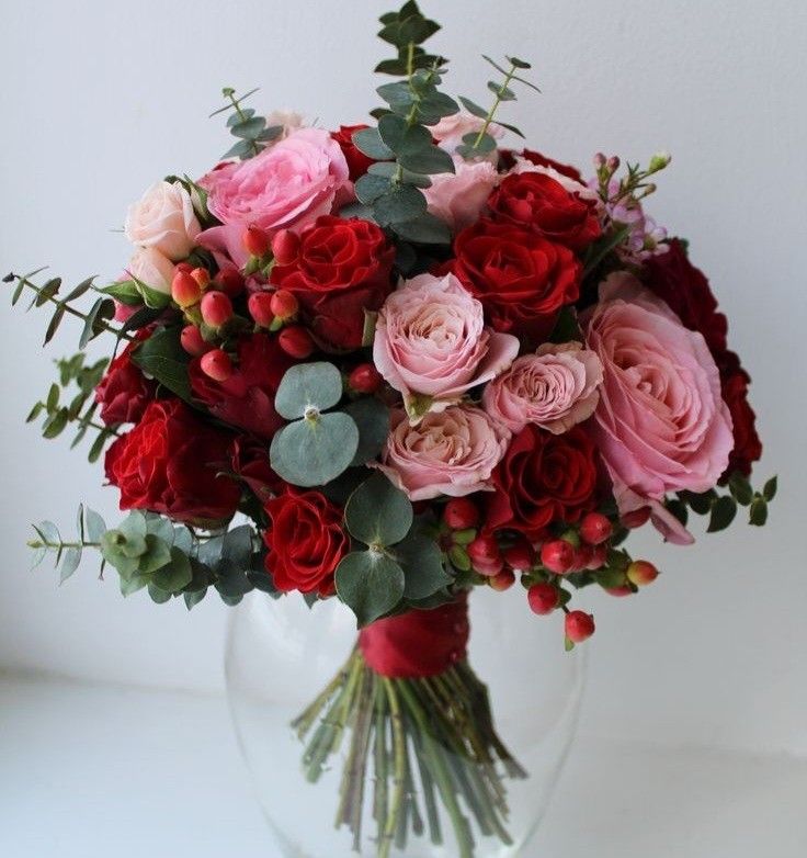 a vase filled with lots of red and pink flowers