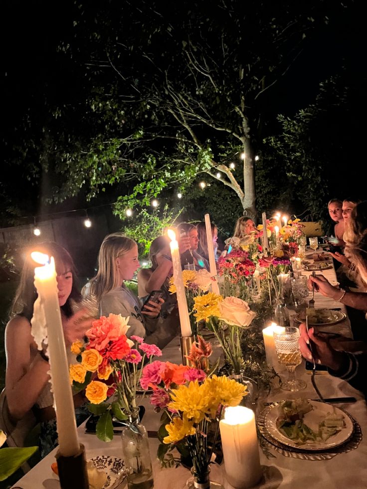 a group of people sitting around a dinner table with lit candles in front of them