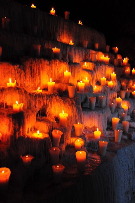 many lit candles are placed on the wall