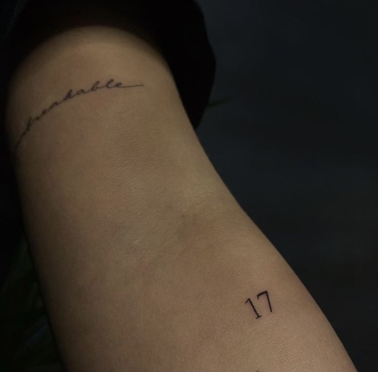 a woman's arm with the number 11 tattooed on her left side, which is written in cursive writing