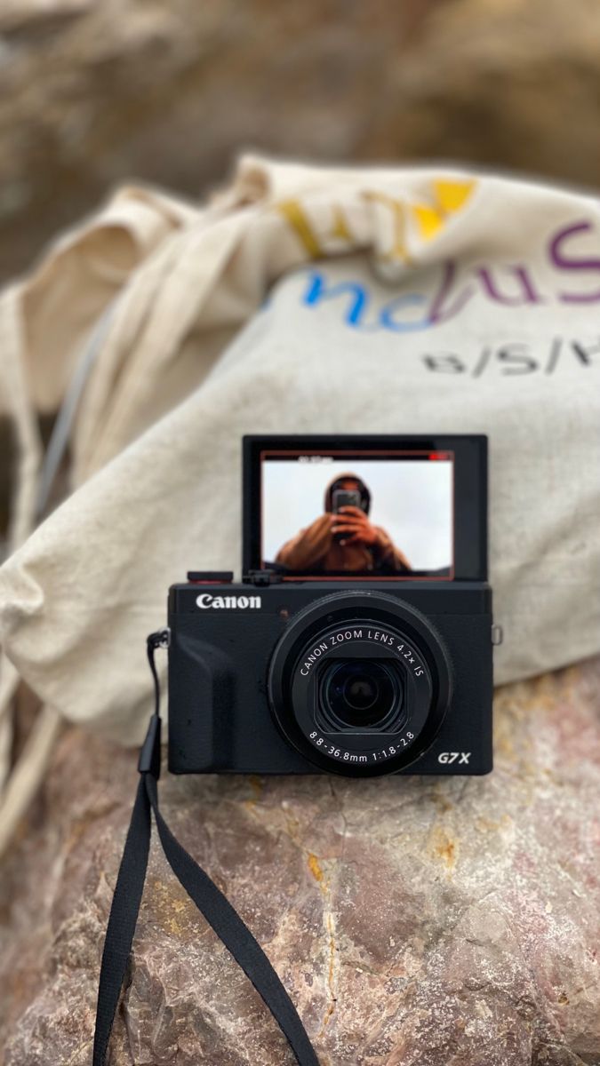 a camera sitting on top of a rock next to a bag