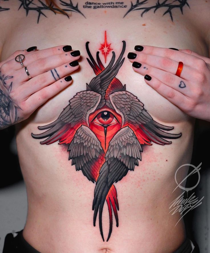 a woman with tattoos on her stomach has an eye and bird tattoo on her chest