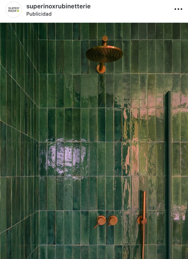 a green tiled shower with copper fixtures