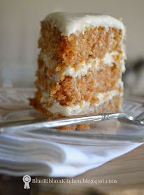 a piece of carrot cake with white frosting on a plate next to a fork