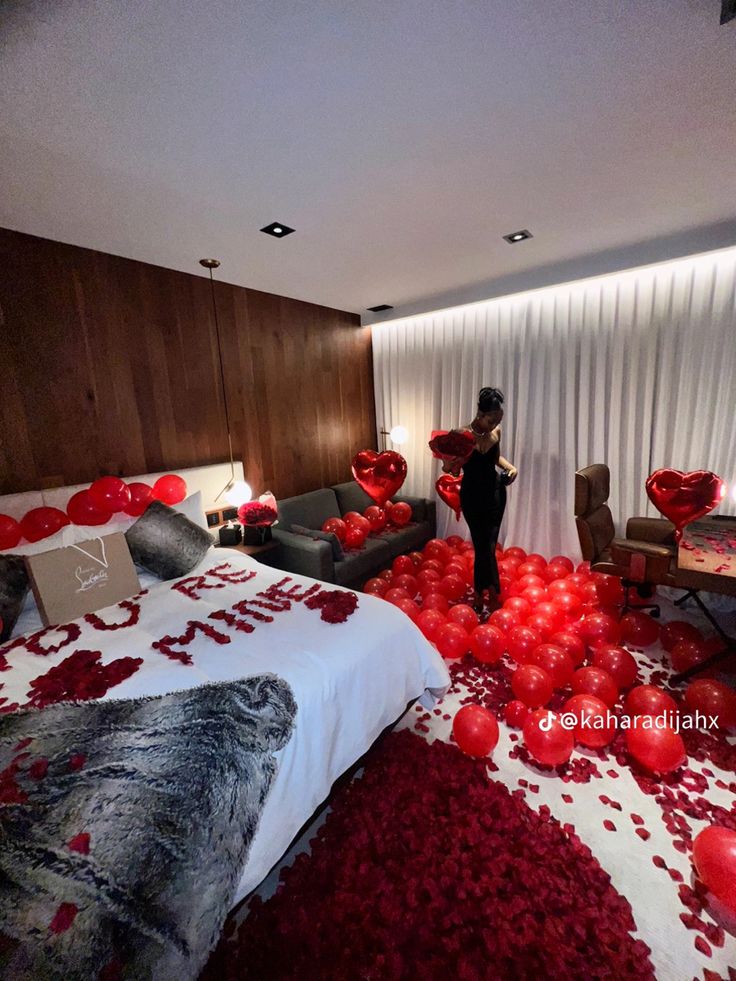 a woman standing in a room filled with red balloons and confetti on the floor