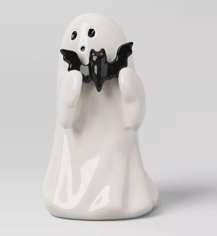 a white ghost figurine holding two black bats in its hands and looking at the viewer